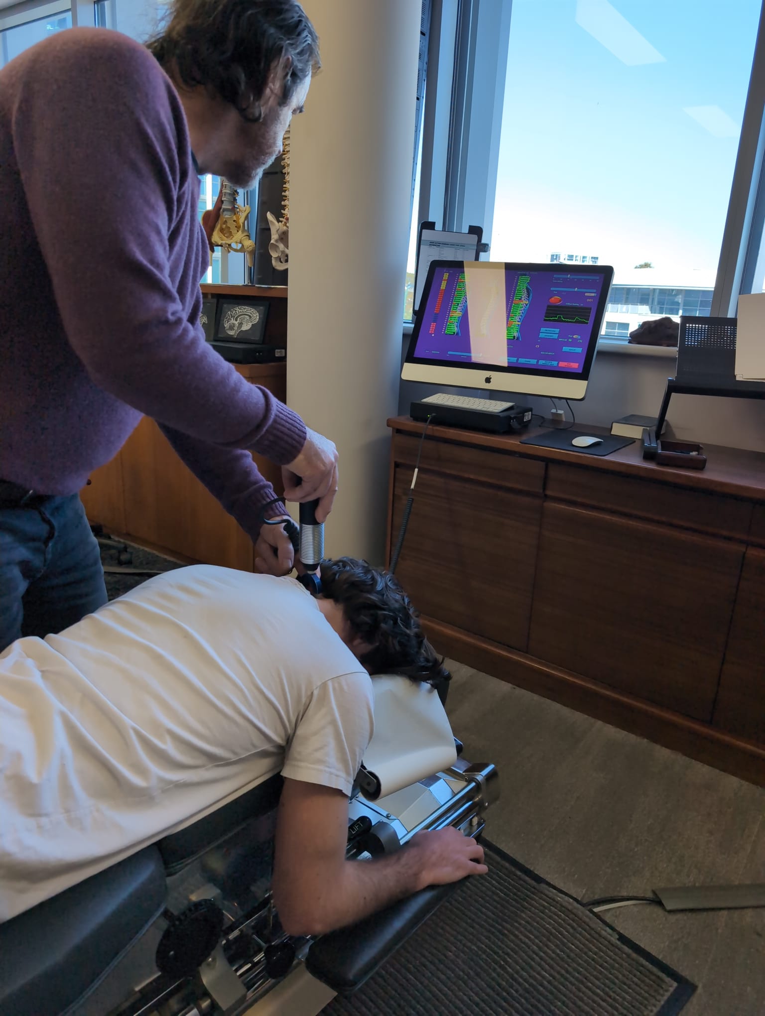 Dr Adam Rocchi using a handheld computerised instrument during a spinal assessment